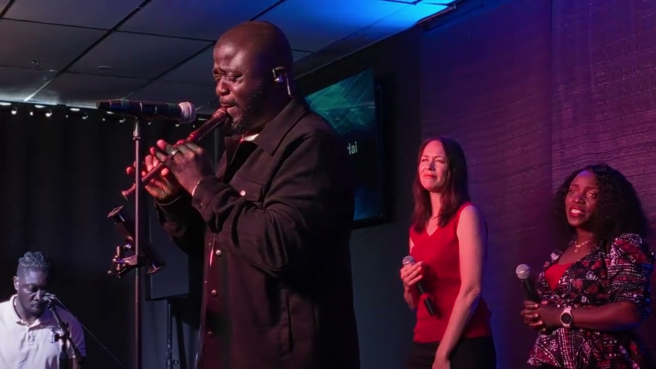 Soji performing live with backing vocalists under purple stage light