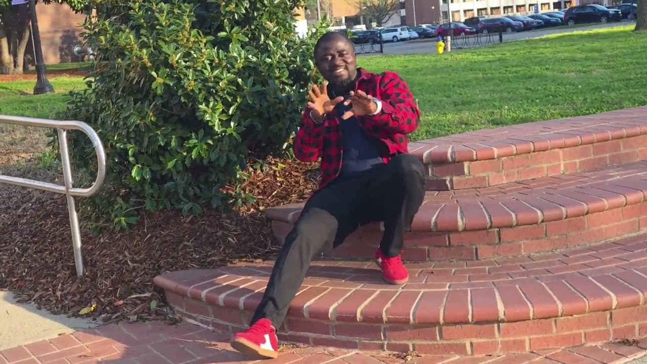 Soji seated on brick steps outdoors, singing